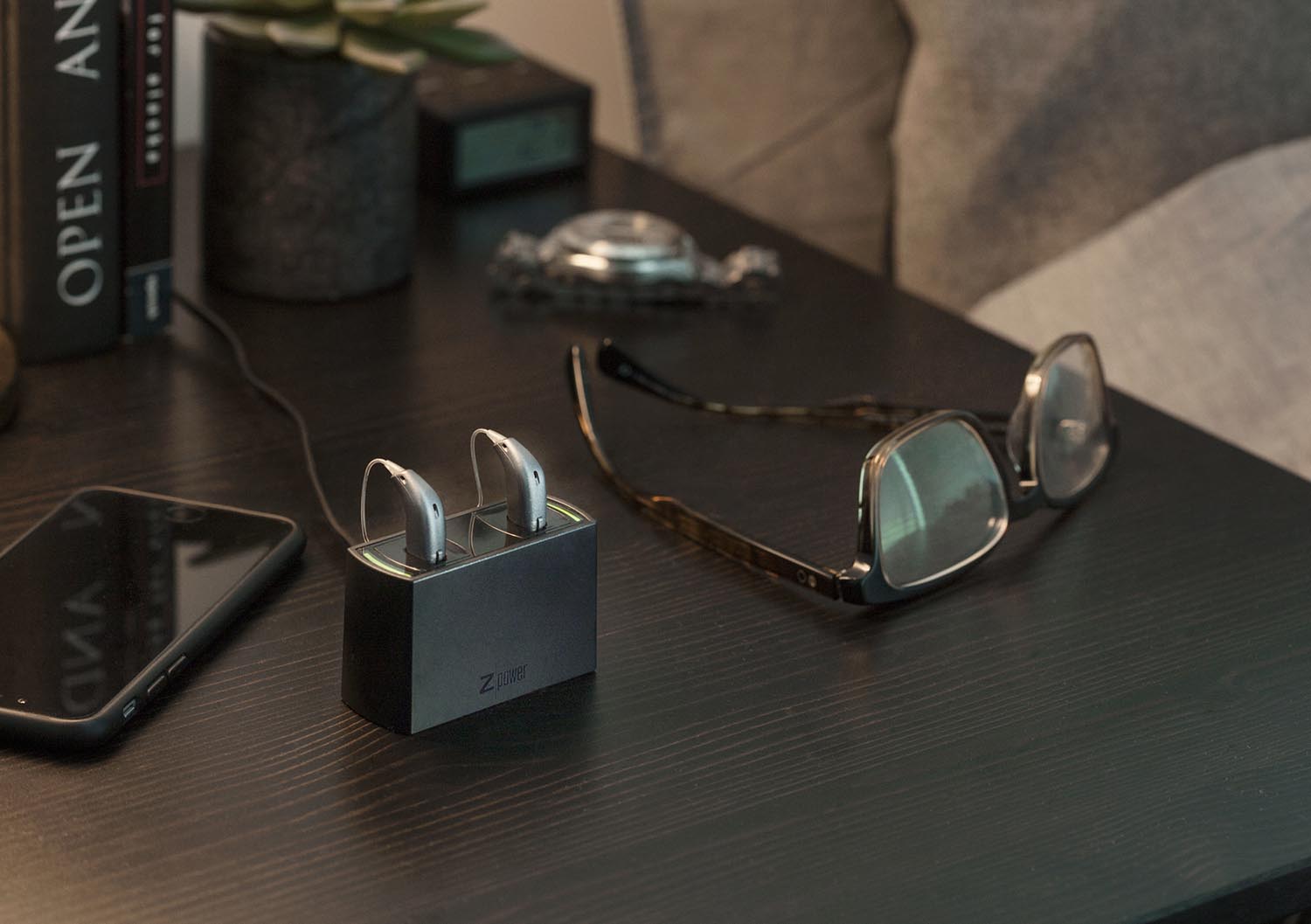 Option Opn hearing aids charging on a bedside table with Z-Power charger