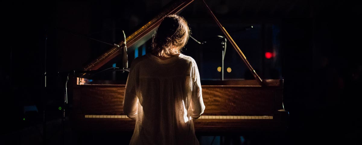 Woman playing piano in a dark concert hall